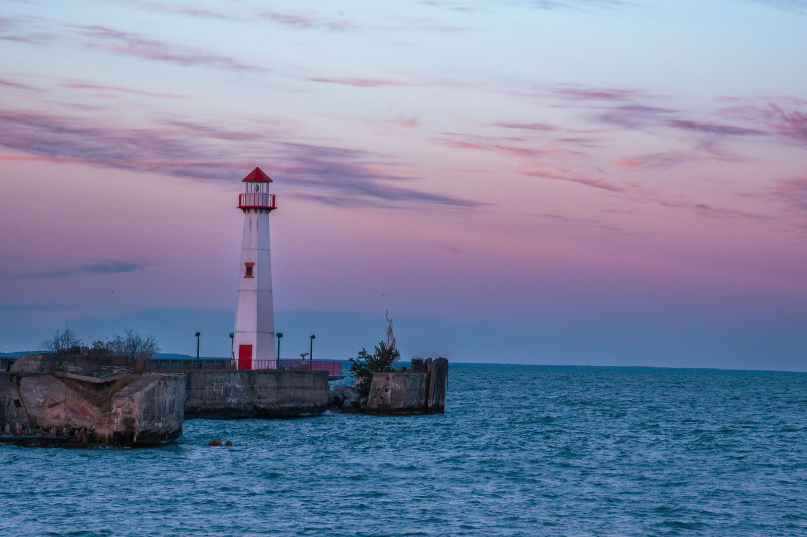 Beautiful view of a lighthouse on Mackinac Island, Michigan at sunset with calm waters and pastel sky.